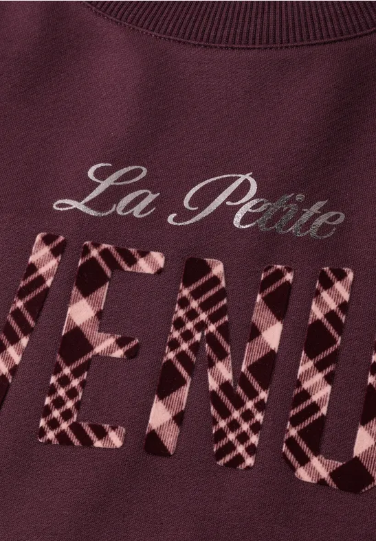 Bordeauxroter Pullover mit der Aufschrift 'La Petite VENUE', das Wort 'VENUE' ist kariert
