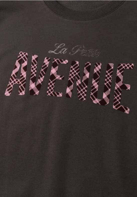 Dunkles T-Shirt mit pink gemustertem Schriftzug 'La Plus AVENUE'.