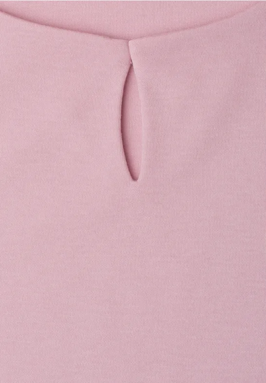 Gros plan sur un haut rose avec petite fente au niveau du col rond.