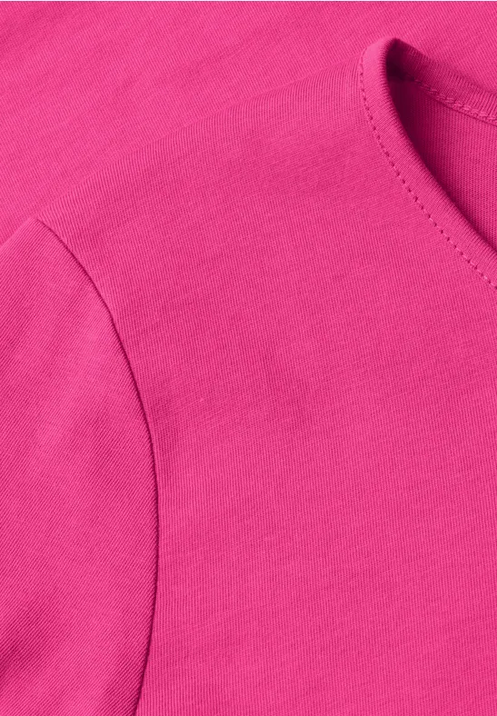 Detailaufnahme eines pinken T-Shirts aus weichem Stoff.