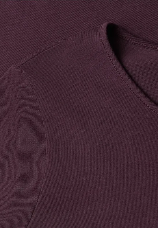 Close-up van een donkerpaars T-shirt, met focus op de halsboord en de naden.