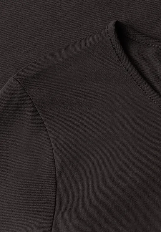 Close-up van een zwart T-shirt met ronde hals en schoudernaad