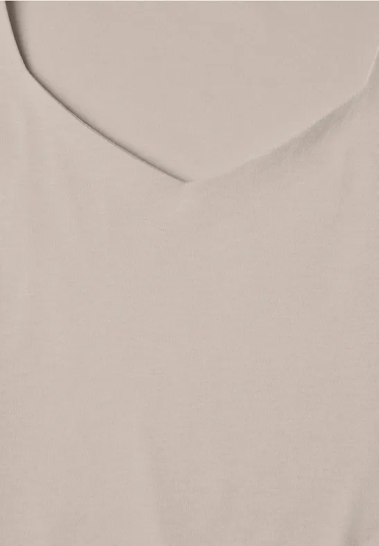 Gros plan sur un tissu beige clair avec une encolure en V.
