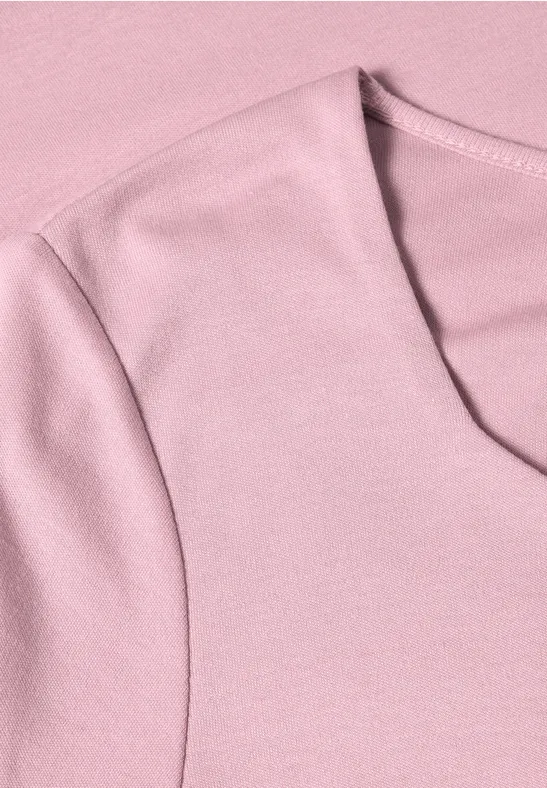 Close-up van een lichtroze katoenen t-shirt met ronde hals en schoudernaden.
