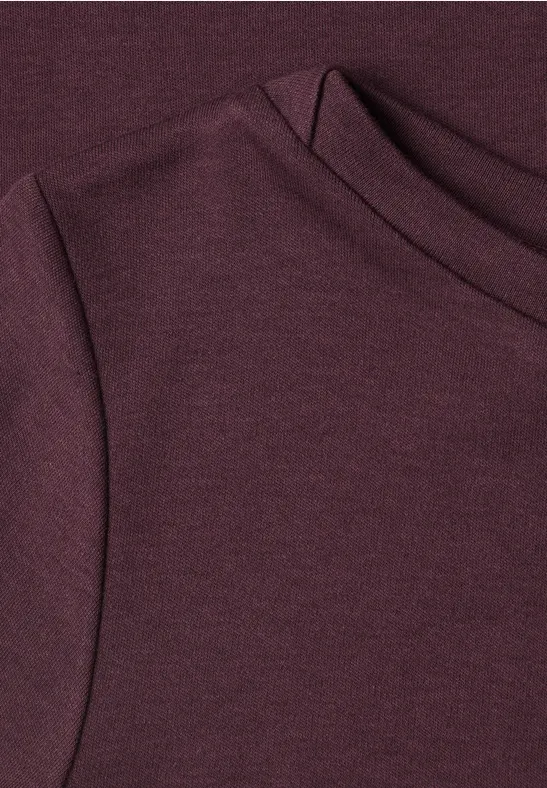 Nahaufnahme eines burgunderfarbenen Strickoberteils mit Rundhalsausschnitt
