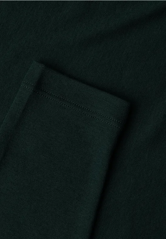 Close-up van een opgestikte zak van donker groen, gestructureerd textiel.