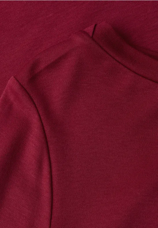 Gros plan d'un vêtement rouge montrant une couture et un col rond