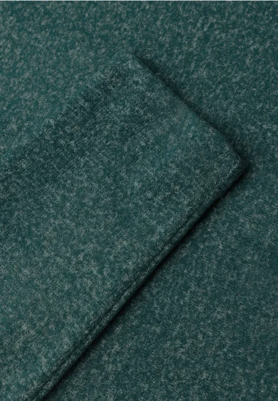 Close-up van een donkergroen, gemêleerd gebreid stof met zichtbare naad.