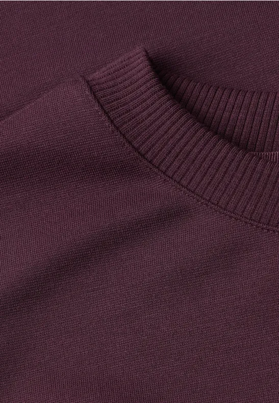 Ausschnitt eines dunkelvioletten Pullis, engmaschig gestrickt, gerippter Rundhalsausschnitt
