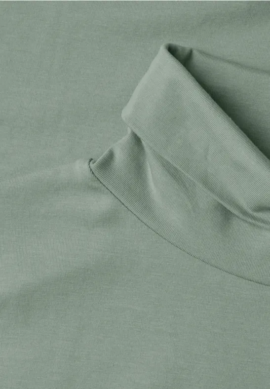 Hellgrüner Rollkragenpullover aus weichem Stoff, flach liegend.