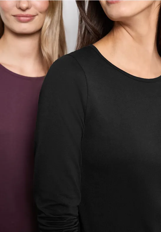 Close-up von zwei Frauen in schlichten Langarm-Shirts in Schwarz und Dunkelrot.