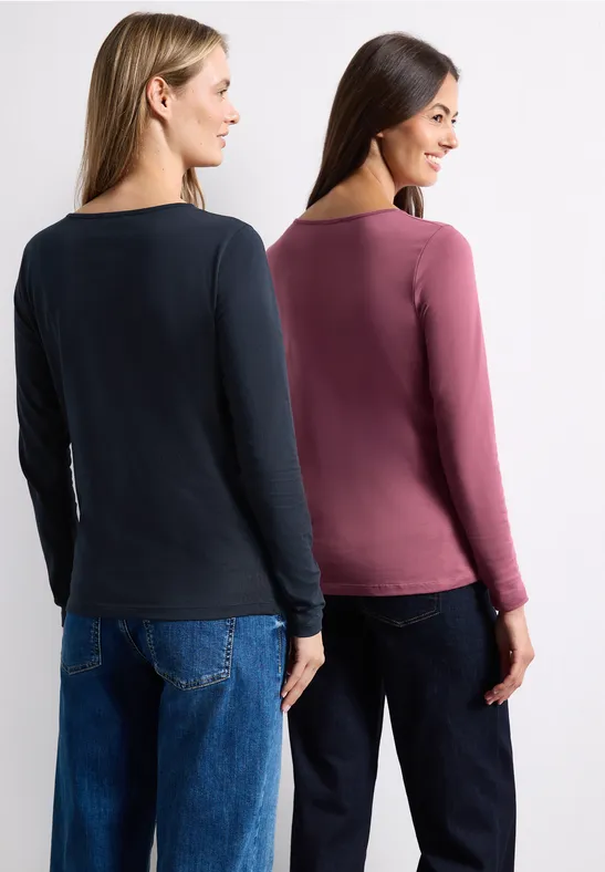 Zwei Frauen von hinten in schlichten Langarmshirts (dunkelblau und rosé) und Jeans.