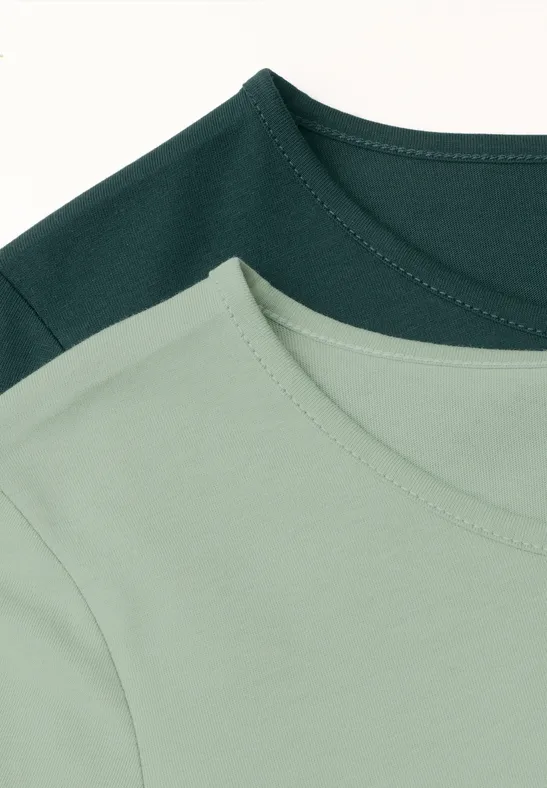 Deux t-shirts sobres, l'un vert clair et l'autre vert foncé, posés à plat avec col rond visible.