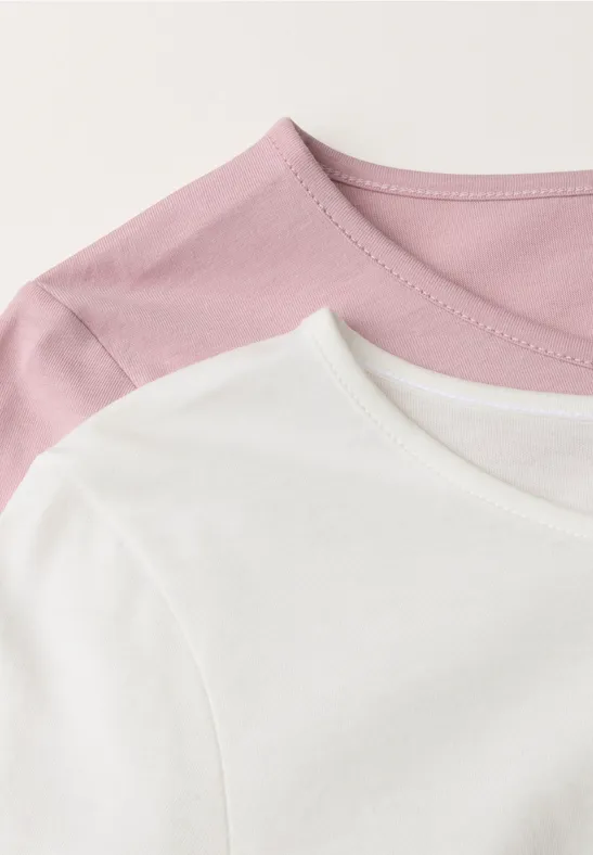 Detailaufnahme von zwei T-Shirts in Rosa und Weiß, leicht übereinandergelegt.