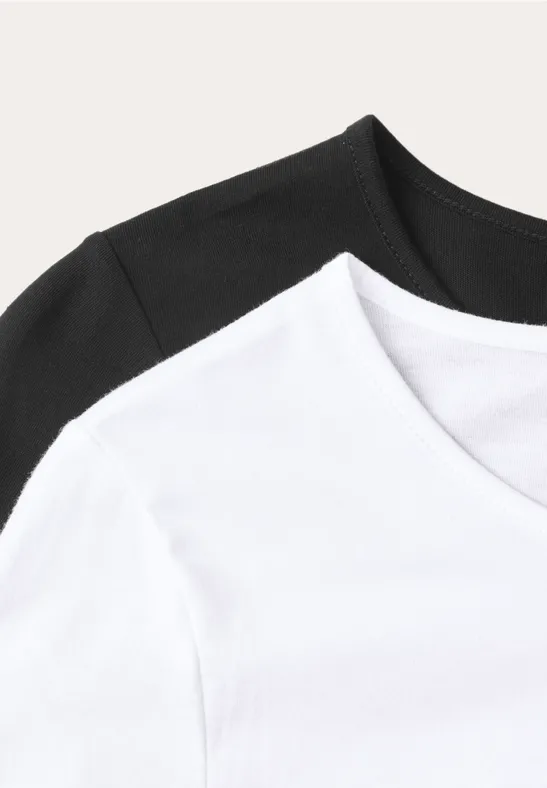 Zwei schlichte T-Shirts (weiß und schwarz) vor hellem Hintergrund.