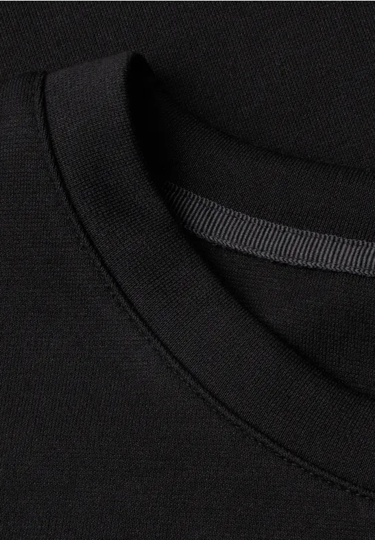 Nahaufnahme eines schwarzen T-Shirts mit Rundhalsausschnitt und feiner Naht.