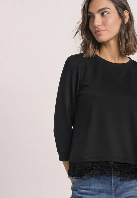 Schwarze Bluse mit Spitzenabschluss am Saum und 3/4-Ärmeln, legerer Schnitt.