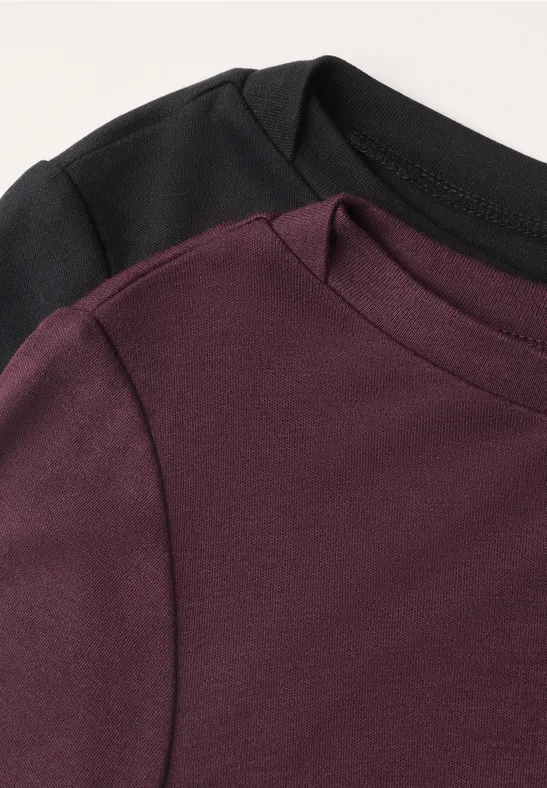 Zwei überlappende T-Shirts in Schwarz und Dunkelrot, Fokus auf den Rundhalsausschnitt und Stoffstruktur.