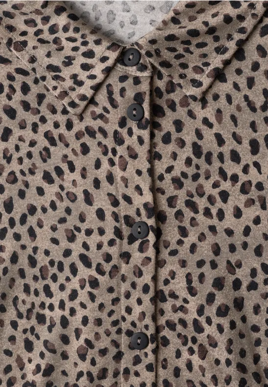 Beiges Hemd mit schwarzen, unregelmäßigen Leopardenflecken, Kragen und Knopfleiste.