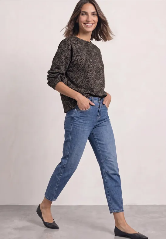 Frau trägt lässiges Outfit aus schwarzem Pullover, blauen Jeans und schwarzen Ballerinas.