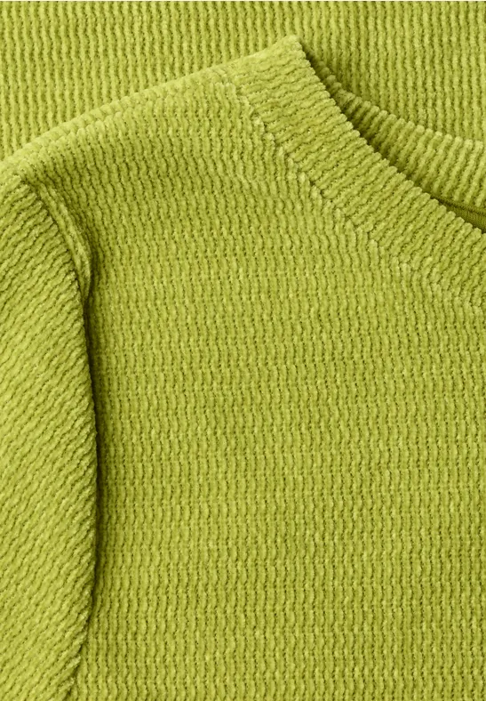 Nahaufnahme eines hellgrünen Strickpullovers mit feiner Textur