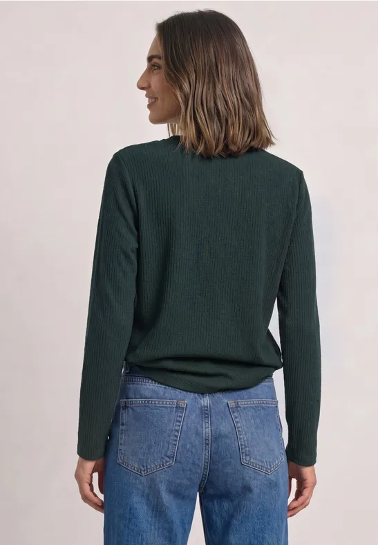 Vrouw van achteren met groene trui en spijkerbroek.