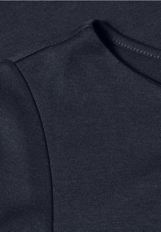 Nahansicht eines schwarzen T-Shirts mit erkennbarer Schulternaht.
