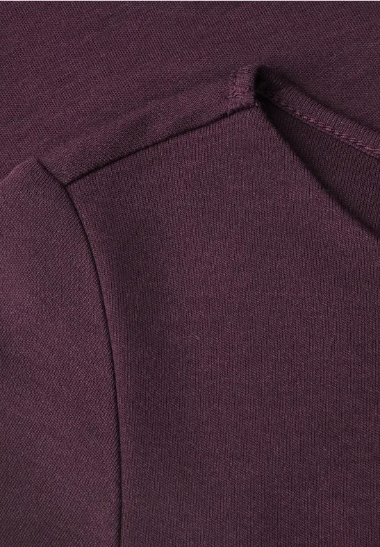 Nahaufnahme eines dunkelvioletten Sweatshirts mit seitlicher Eingrifftasche und weichem Stoff