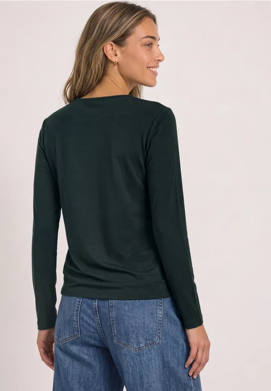 Vrouw van achteren in zwart shirt met lange mouwen en blauwe jeans, schuin staand.