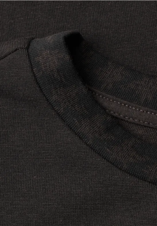 Nahaufnahme des Kragens und der Stoffstruktur eines dunklen T-Shirts.