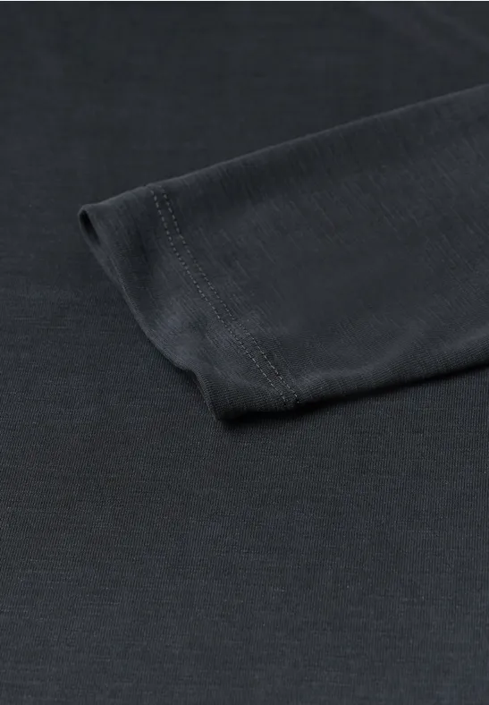 Close-up van de zwarte mouw van een T-shirt liggend op een witte achtergrond.