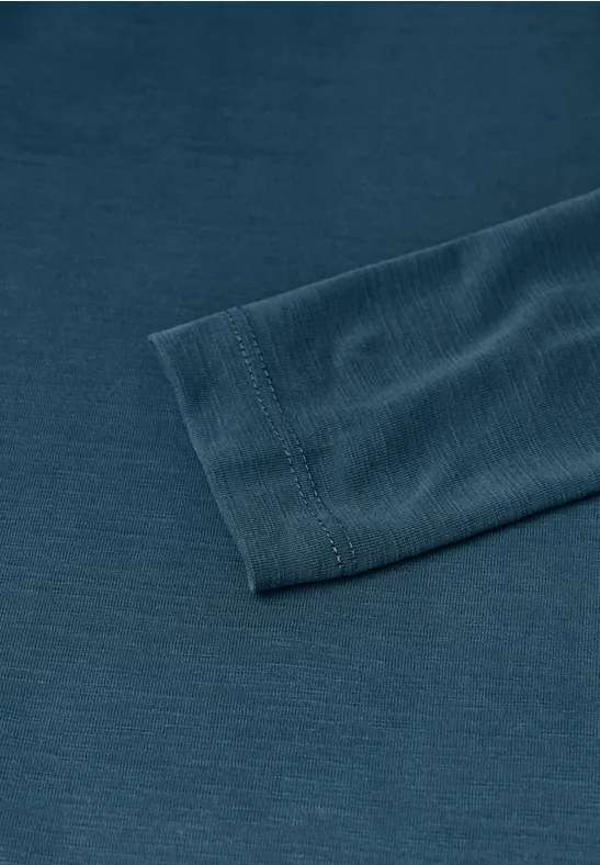 Close-up van een donkergroen shirt met lange mouwen en geribde manchetten, op een effen ondergrond.