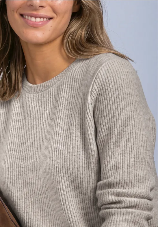 Femme souriante en pull côtelé beige, en pose décontractée.