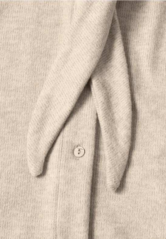 Beige Strickjacke mit Knopf und zwei spitz zulaufenden Zipfeln.