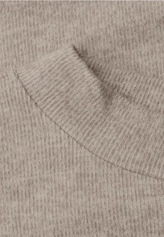 Nahaufnahme eines beigen Strickpullovers mit Rundhalsausschnitt.