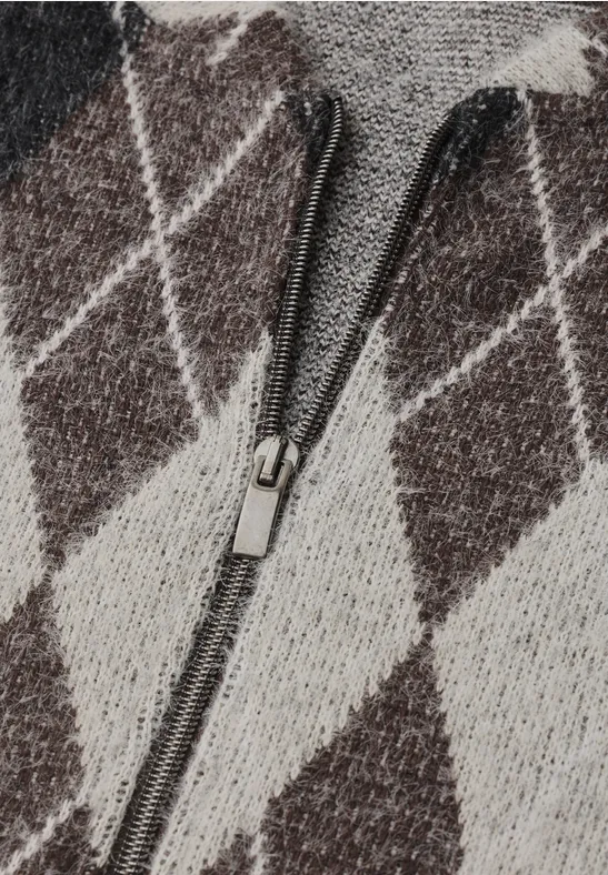 Nahaufnahme eines Strick-Pullovers mit beigefarbenem Rautenmuster und mittigem Reißverschluss.