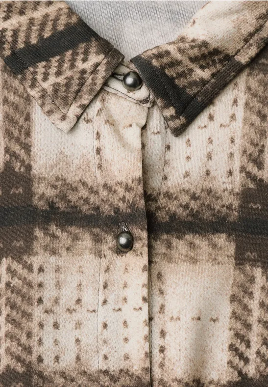 Nahaufnahme einer karierten Jacke in Beige- und Brauntönen mit Metallknöpfen.