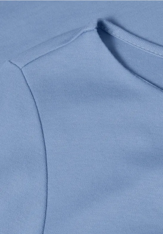 Nahaufnahme eines hellblauen T-Shirts oder Oberteils mit erkennbarer Schulternaht.