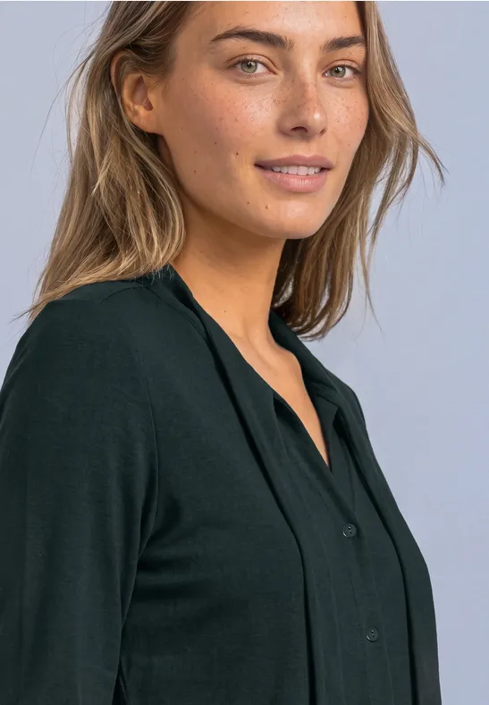 Portret van een glimlachende vrouw met lichte ogen en een zwarte blouse voor een lichte achtergrond.