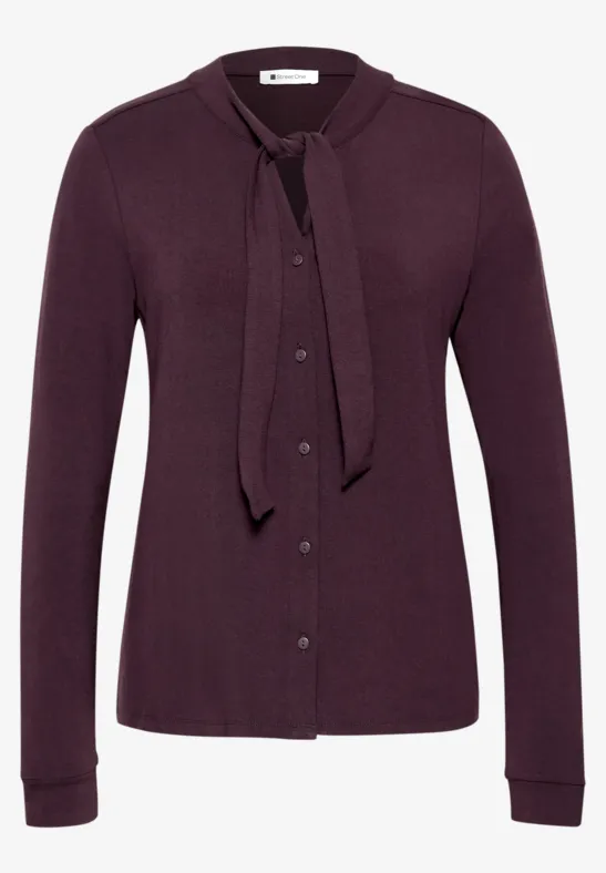Lila Strickjacke mit Knopfleiste und Schleifenkragen, langärmlig.