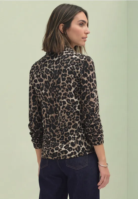 Frau von hinten mit braunem, langärmligem Leopardenmuster-Oberteil und dunklen Jeans
