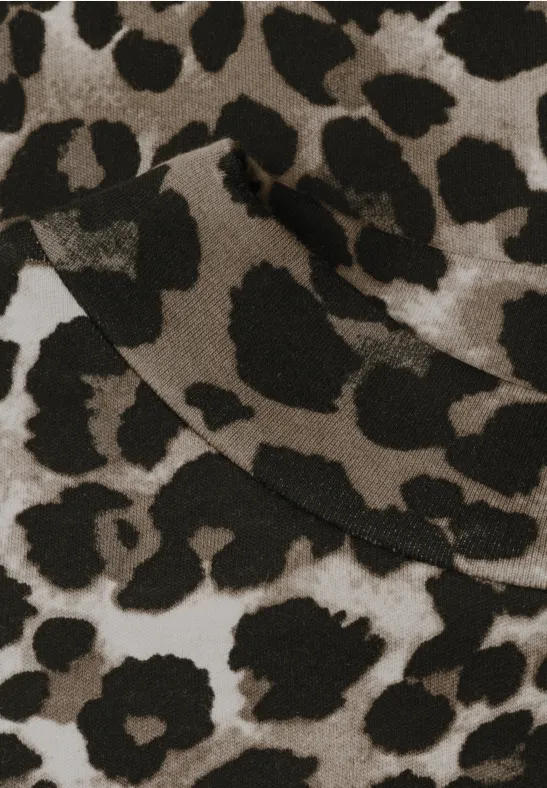 Naheinstellung eines beigen Stoffstücks mit markantem schwarzen Leopardenmuster.