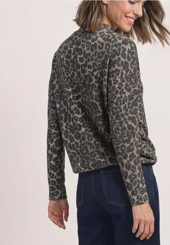 Frau trägt lockeres, langärmeliges Oberteil mit Leopardenmuster und dunkle Jeans von hinten.