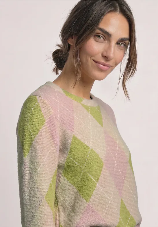 Frau mit zurückgebundenem Haar und leichtem Lächeln trägt einen rosa-grünen Rautenmuster-Pullover.