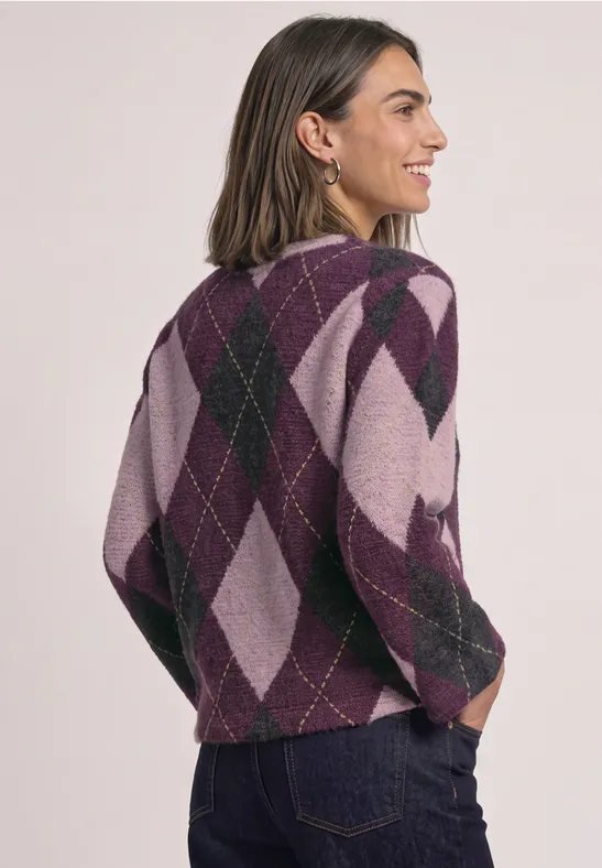 Frau in violett-rosafarbenem Argyle-Pullover zeigt Rückansicht, trägt Jeans.