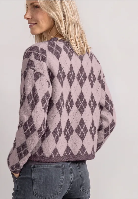 Rückansicht einer Frau mit blondem Haar in einem violetten, rautenförmigen Strickpullover.