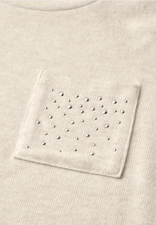 Beiges Shirt mit aufgesetzter Tasche, dekoriert mit gleichmäßig verteilten kleinen Perlen.