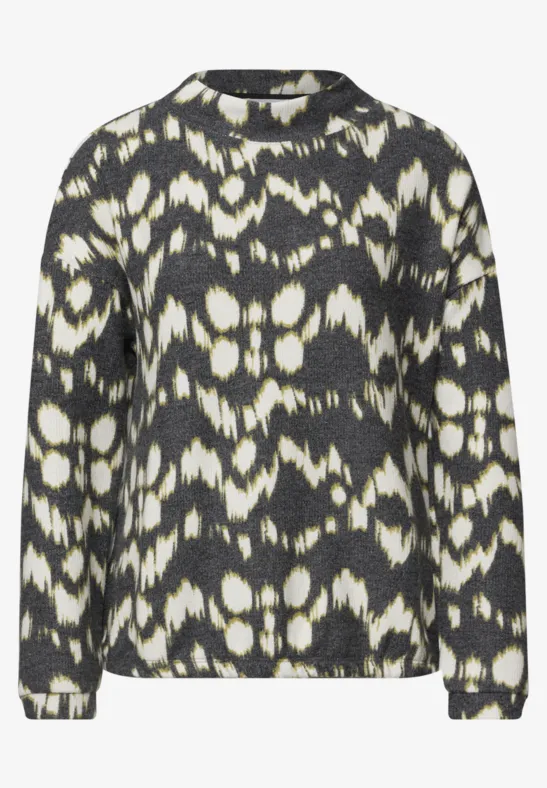 Schwarzer und weißer Pullover mit abstraktem Batik-/Ikat-Muster, Rundhalsausschnitt und langen Ärmeln.
