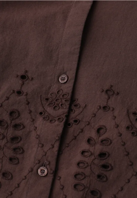 Chemisier marron à broderies florales et découpes, patte de boutonnage visible.