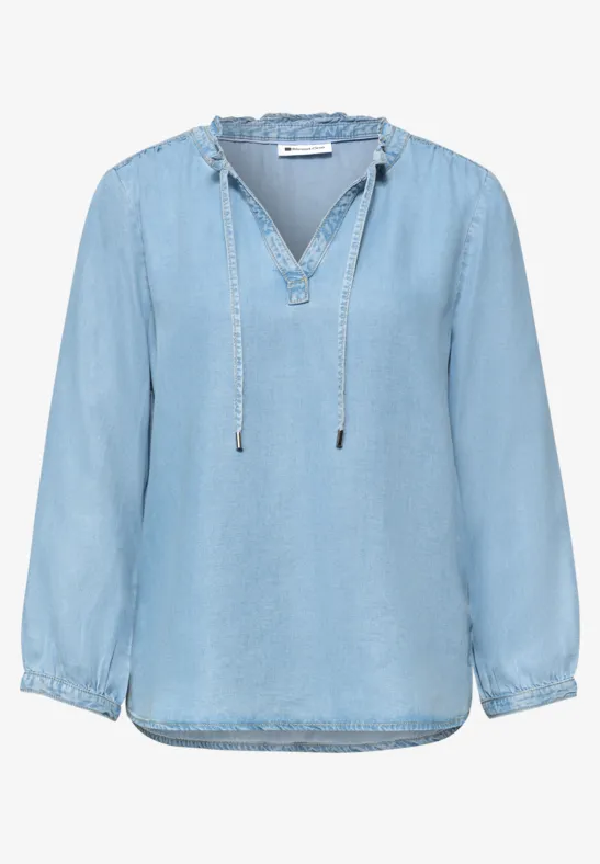Lichtblauwe denimblouse met V-hals, koordjes en lange mouwen, losse pasvorm.